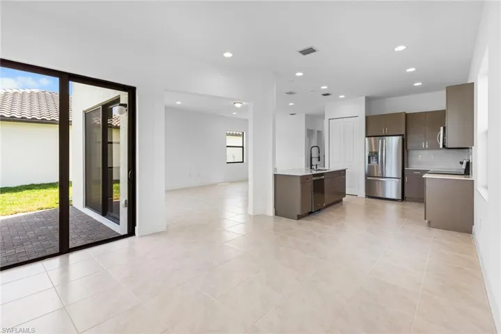 Kitchen with stainless steel appliances, recessed lighting, open floor plan, light stone countertops, and light tile patterned flooring
