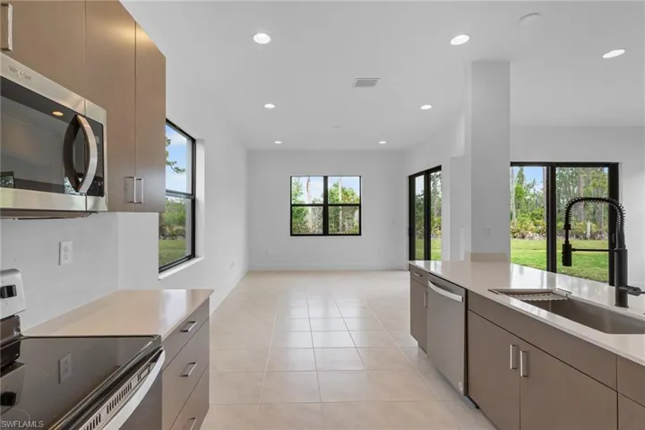 Kitchen with stainless steel appliances, light tile patterned floors, recessed lighting, light stone counters, and modern cabinets