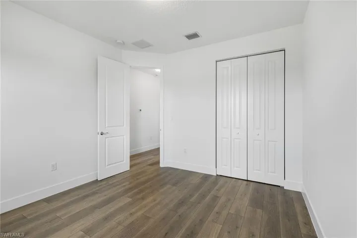 Unfurnished bedroom featuring a closet, dark wood-style flooring, and a textured ceiling
