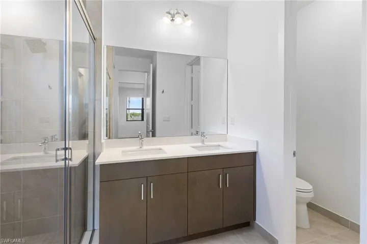 Bathroom featuring a stall shower, double vanity, and light tile patterned floors
