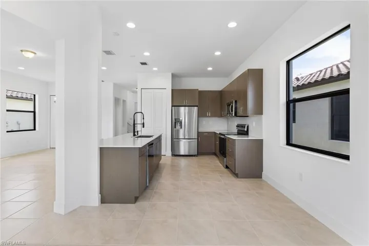 Kitchen with stainless steel appliances, light tile patterned floors, recessed lighting, dark wood finish cabinets, and modern cabinets