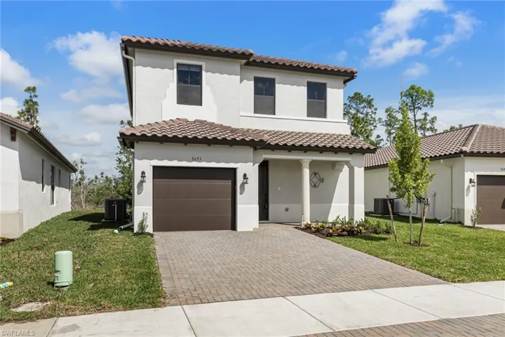 Mediterranean / spanish house featuring a front yard, stucco siding, and decorative driveway