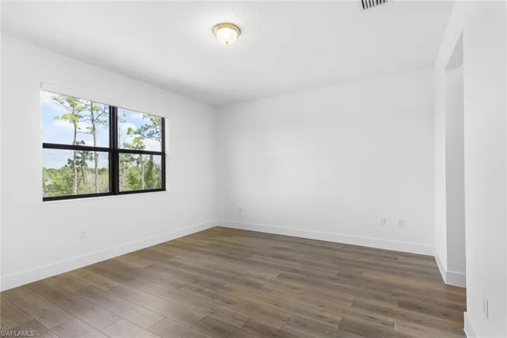 Empty room featuring dark wood-style floors and baseboards