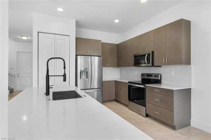 Kitchen with stainless steel appliances, light tile patterned floors, light stone counters, modern cabinets, and recessed lighting