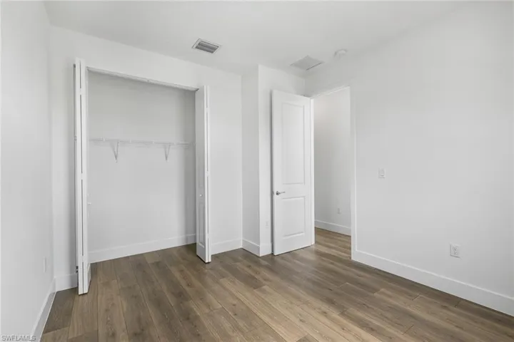 Unfurnished bedroom featuring dark wood-style floors and a closet