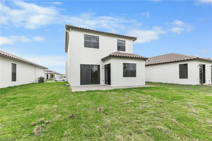 Back of property with stucco siding, a lawn, a patio area, and a tile roof