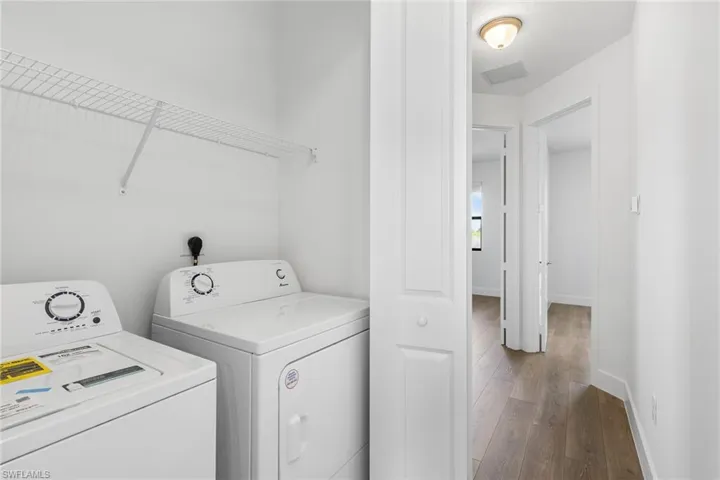 Laundry area with hardwood / wood-style flooring and washer and clothes dryer