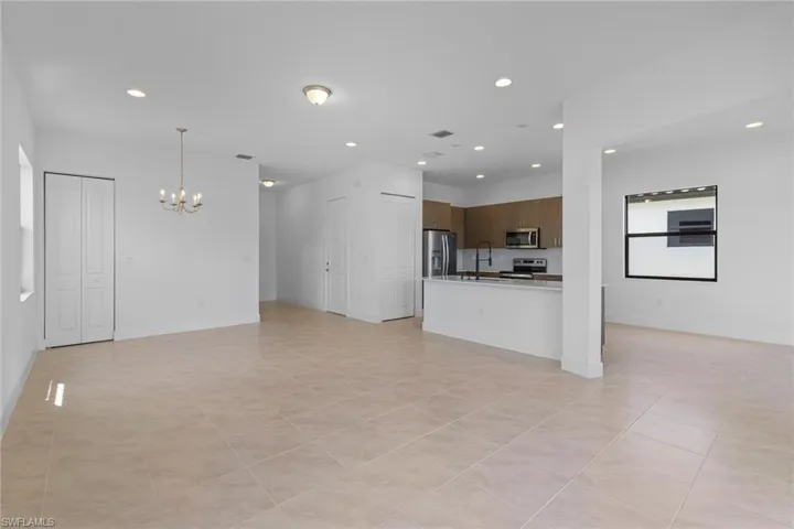 Unfurnished living room with a chandelier and light tile patterned flooring