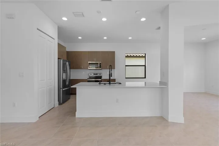 Kitchen with stainless steel appliances, recessed lighting, a peninsula, modern cabinets, and light tile patterned flooring