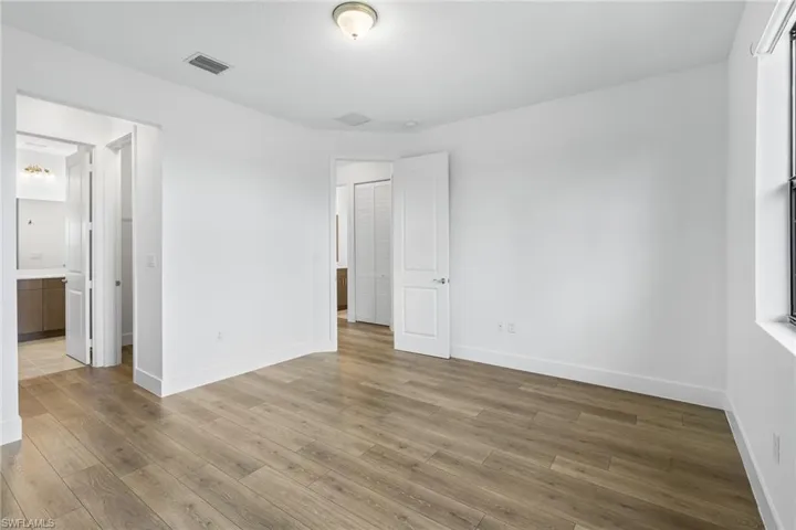 Unfurnished bedroom with wood finished floors and a walk in closet