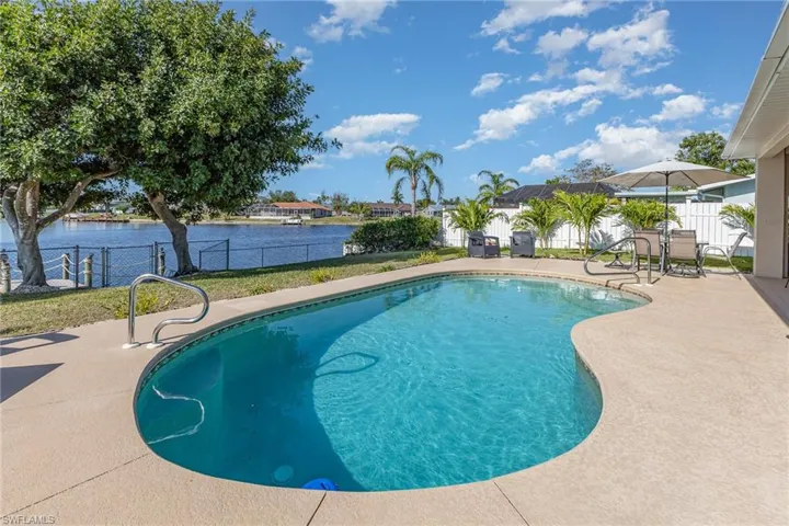 Freeform swimming pool with integrated handrail, surrounded by a paved deck