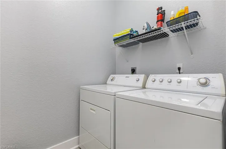 Laundry area with a white washer and dryer set, featuring a wire shelving unit for storage