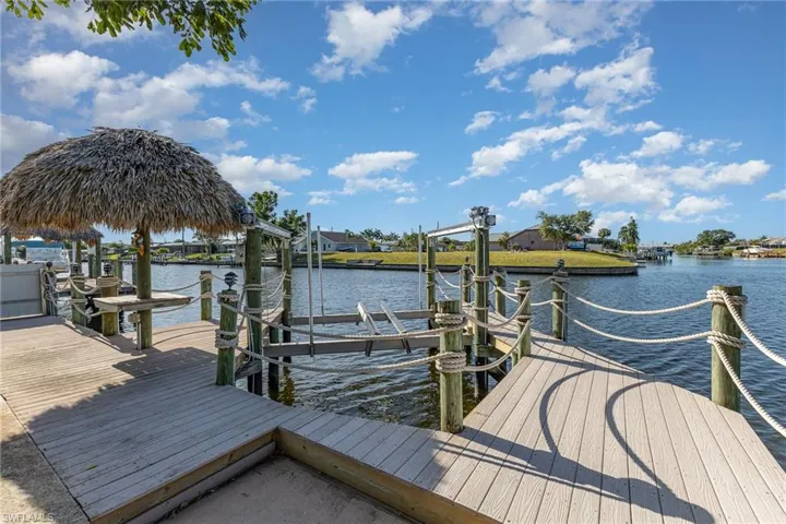 Waterfront dock with composite decking, featuring a thatched tiki hut and a boat lift