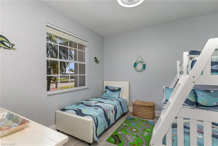 Room featuring a multi-pane window with blinds, wood-finish flooring, and a ceiling-mounted light fixture