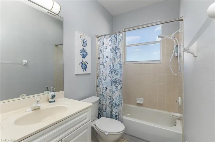 Bathroom featuring a single vanity with an integrated sink, a large mirror, a toilet, and a combination tub and shower