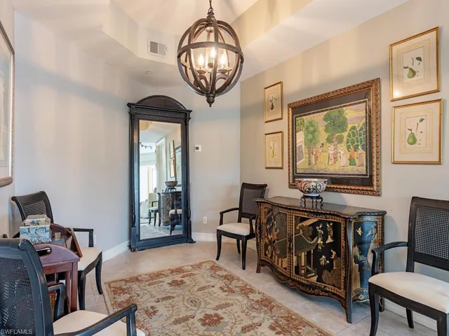 Living area featuring light tile patterned flooring, a chandelier, and a raised ceiling