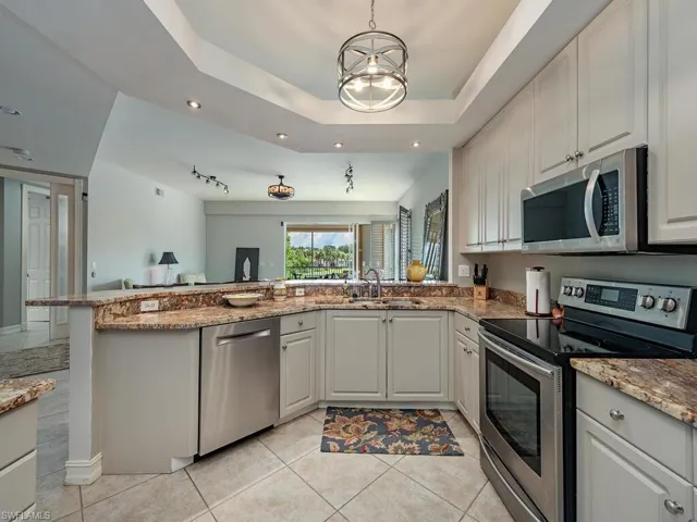 Kitchen featuring a tray ceiling, appliances with stainless steel finishes, sink, and kitchen peninsula