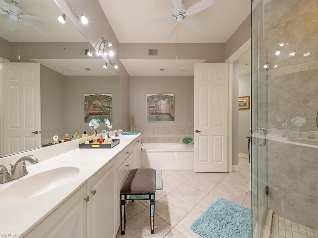 Bathroom featuring tile patterned flooring, shower with separate bathtub, dual vanity, and ceiling fan