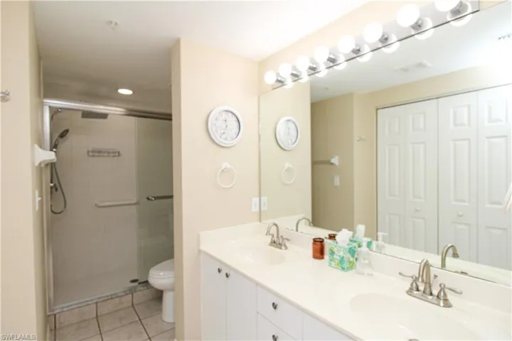 Bathroom featuring walk in shower, tile patterned floors, double sink vanity, and toilet