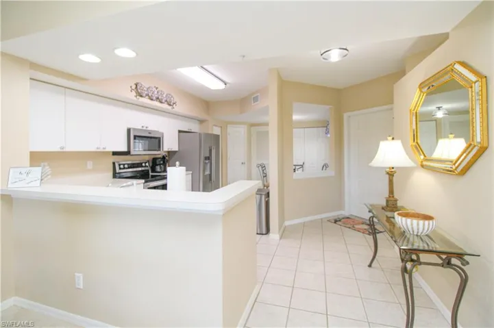 Kitchen with white cabinetry, appliances with stainless steel finishes, light tile patterned floors, and kitchen peninsula