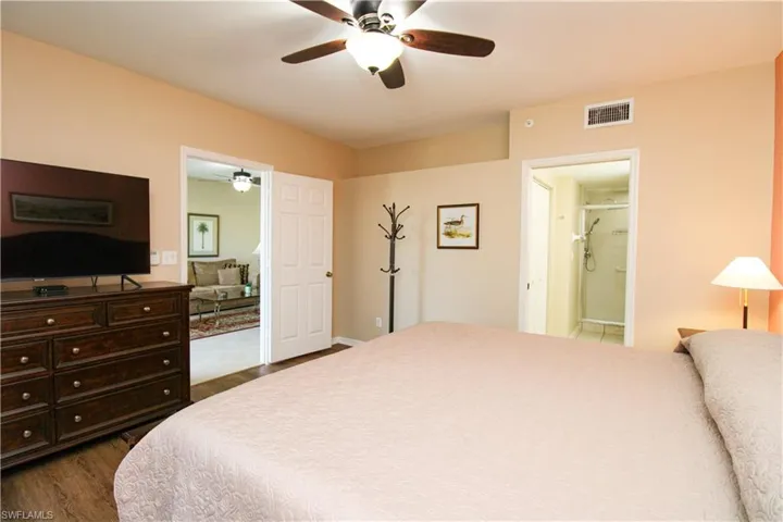 Bedroom featuring ensuite bath, dark hardwood / wood-style floors, and ceiling fan