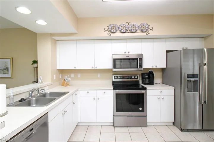 Kitchen with white cabinets, light tile patterned flooring, appliances with stainless steel finishes, and sink