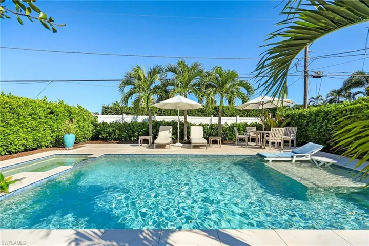 Beautiful oasis pool with sun shelf, hot tub, seating, and privacy.