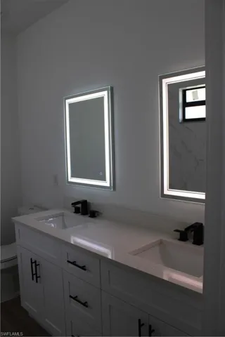 Full bathroom with double vanity and toilet