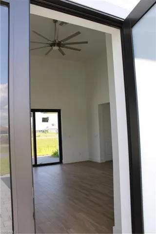 Empty room featuring wood finished floors, a high ceiling, and a ceiling fan
