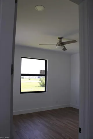 Unfurnished room featuring dark wood finished floors and ceiling fan