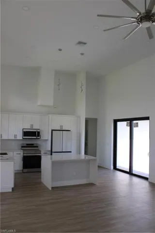 Kitchen featuring a high ceiling, stove, a center island, refrigerator, and light wood finished floors
