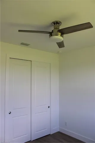 Unfurnished bedroom with dark wood-type flooring, ceiling fan, and a closet