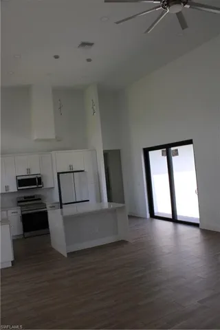 Kitchen featuring a kitchen island, a high ceiling, stove, refrigerator, and white cabinets