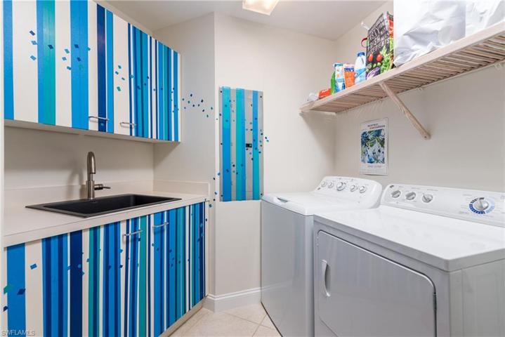 Laundry room with newer washer and dryer, and storage shelves.
