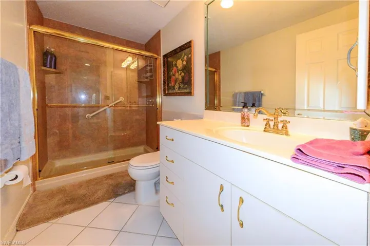 Bathroom with vanity, a shower with shower door, tile patterned floors, and toilet