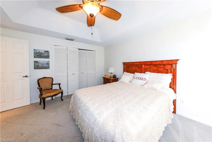 Bedroom with lofted ceiling, light carpet, a raised ceiling, a closet, and ceiling fan