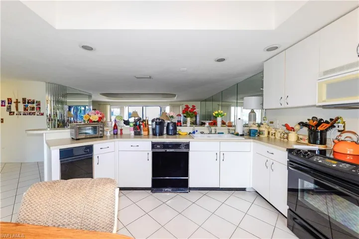 Kitchen featuring black appliances, sink, white cabinets, and kitchen peninsula