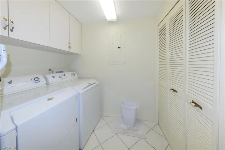 Washroom featuring separate washer and dryer, electric panel, cabinets, and light tile patterned flooring