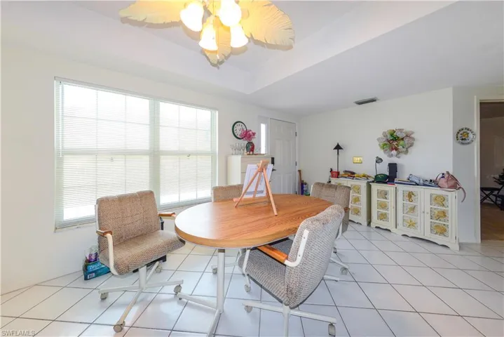 Dining room featuring a raised ceiling, light tile patterned flooring, and ceiling fan