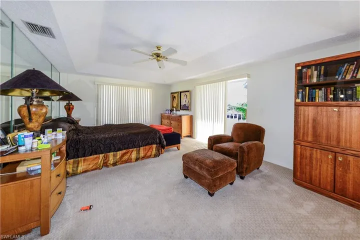 Carpeted bedroom featuring access to outside, ceiling fan, and a tray ceiling