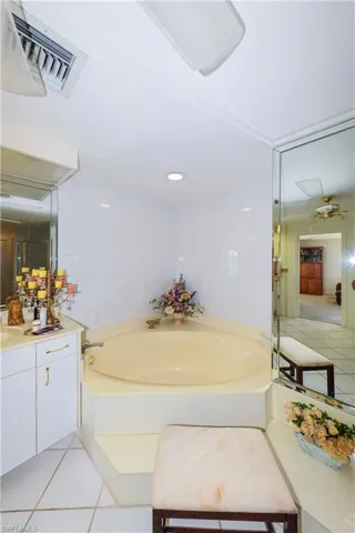 Bathroom with vanity, a bath, tile patterned flooring, and tile walls