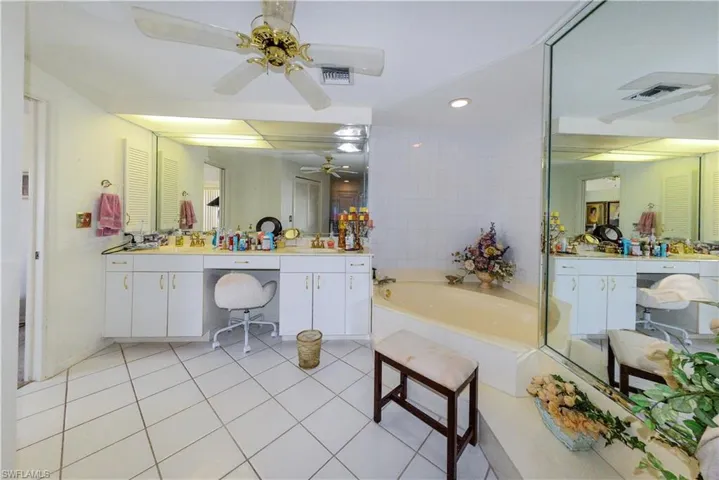 Bathroom featuring ceiling fan, tile walls, a bathtub, vanity, and tile patterned floors