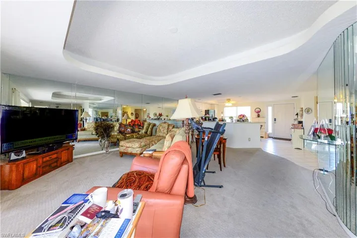 Carpeted living room featuring ceiling fan, a raised ceiling, and a textured ceiling