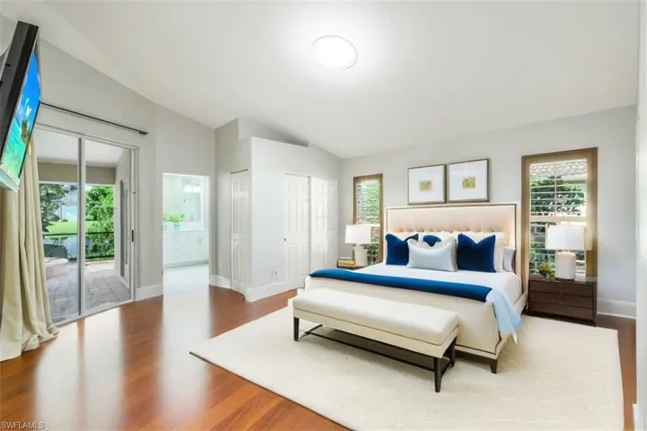 Bedroom featuring hardwood / wood-style flooring, vaulted ceiling, and multiple windows