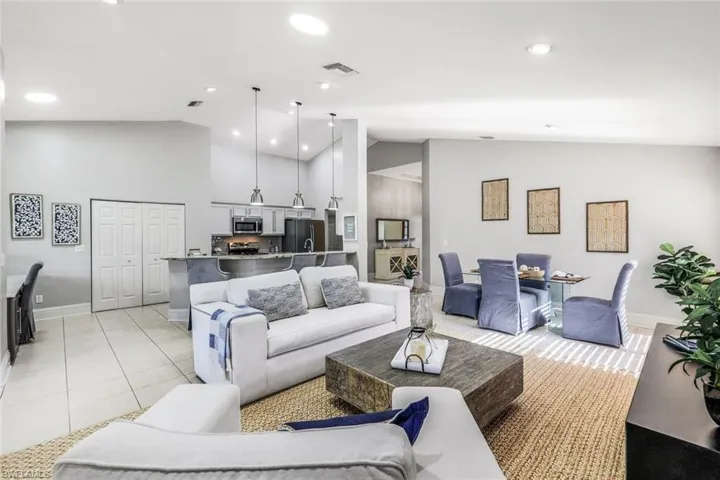 Living room with light tile patterned flooring and high vaulted ceiling