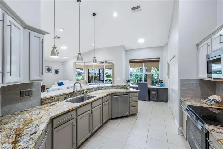 Kitchen featuring decorative light fixtures, sink, light stone countertops, appliances with stainless steel finishes, and light tile patterned floors