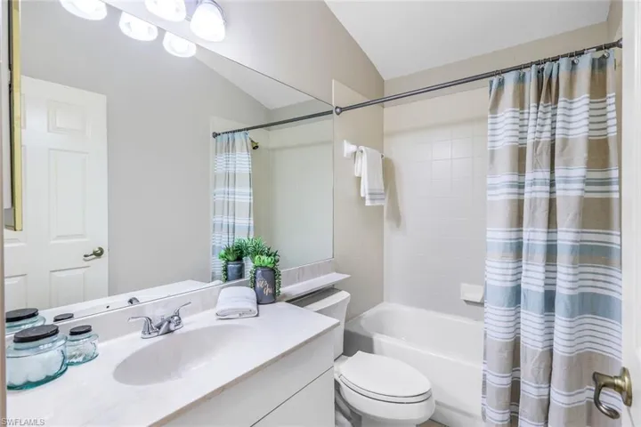 Full bathroom featuring vaulted ceiling, vanity, shower / bath combo, and toilet