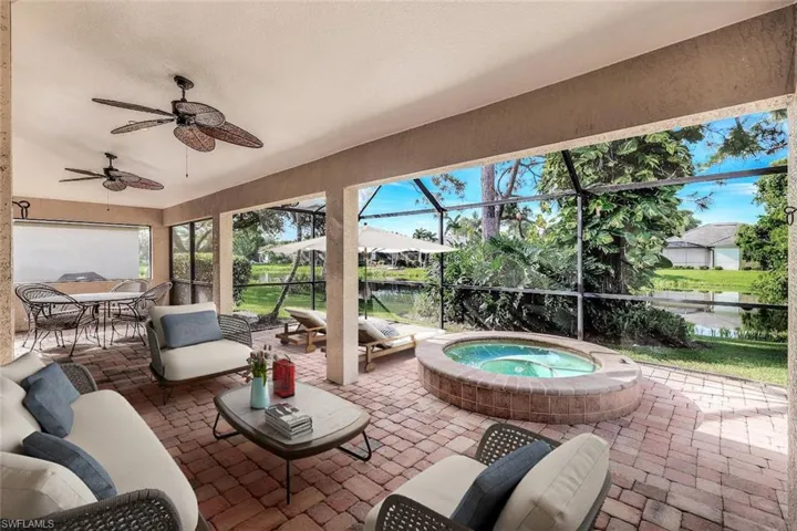 View of patio with an in ground hot tub, ceiling fan, and glass enclosure