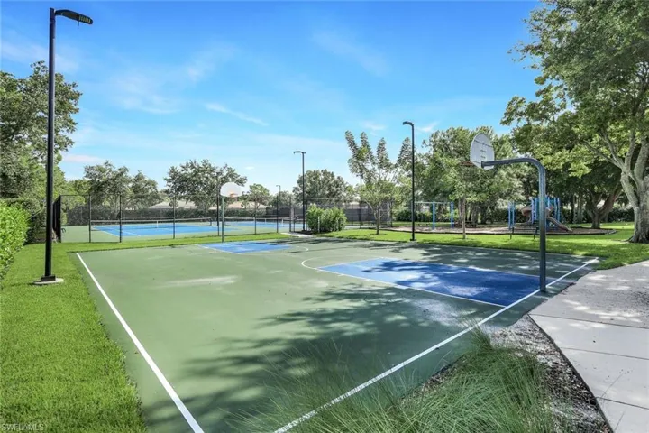 View of sport court featuring a playground and a lawn