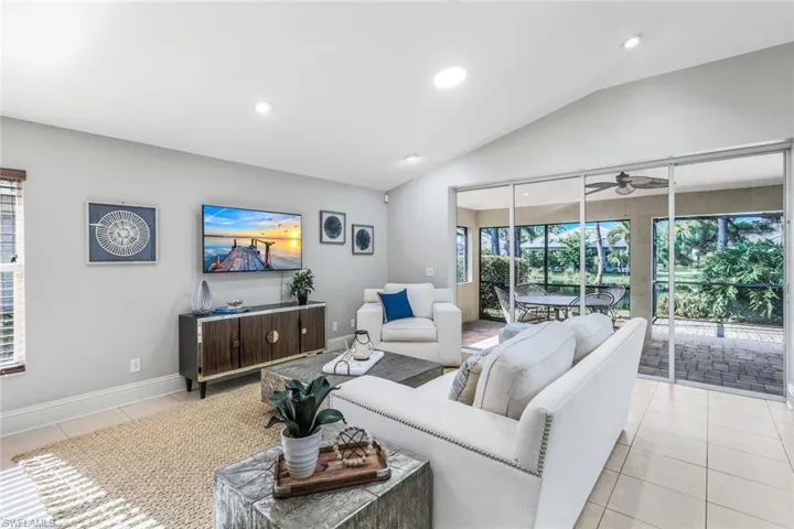Living room with light tile patterned floors, vaulted ceiling, and ceiling fan